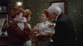 Movie still from “The Dead” (1987), directed by John Huston – A group of people standing around each other in a room; Medium shot, High angle