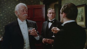 Movie still from “The Dead” (1987), directed by John Huston – A group of men standing next to each other holding wine glasses; Medium shot, Low angle