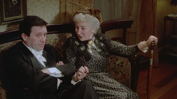 Movie still from “The Dead” (1987), directed by John Huston – An older woman sitting next to an older man; Medium shot, High angle