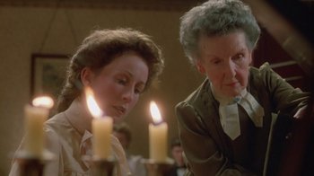 Movie still from “The Dead” (1987), directed by John Huston – Two women standing in front of lit candles; Close Up shot, Over the shoulder angle