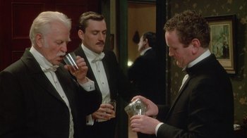 Movie still from “The Dead” (1987), directed by John Huston – A group of men standing next to each other holding drinks; Medium shot, High angle