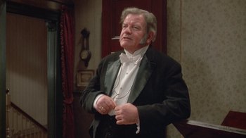 Movie still from “The Dead” (1987), directed by John Huston – An older man in a tuxedo smoking a cigarette; Medium shot, Low angle