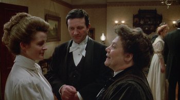 Movie still from “The Dead” (1987), directed by John Huston – Two women and a man are talking in a living room; Medium shot, Over the shoulder angle