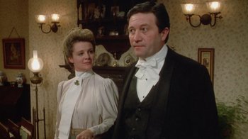 Movie still from “The Dead” (1987), directed by John Huston – A man and a woman standing next to each other in a room; Medium shot, Low angle