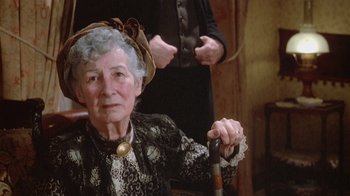 Movie still from “The Dead” (1987), directed by John Huston – An older woman sitting in a chair holding a walking stick; Close Up shot, High angle