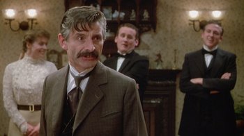 Movie still from “The Dead” (1987), directed by John Huston – A man in a suit standing in front of another man in a suit; Medium shot, Over the shoulder angle