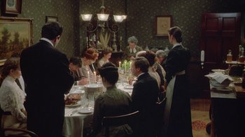 Movie still from “The Dead” (1987), directed by John Huston – A group of people sitting around a table with food on top of it; Wide shot, High angle