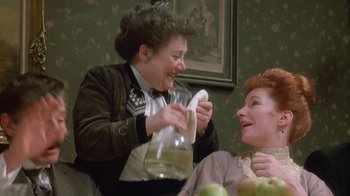 Movie still from “The Dead” (1987), directed by John Huston – Two women sitting in a room one is holding a napkin and the other is holding an apple; Medium shot, High angle