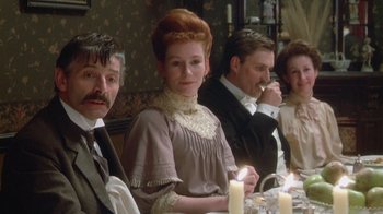 Movie still from “The Dead” (1987), directed by John Huston – A group of people sitting at a table with candles; Medium shot, Over the shoulder angle
