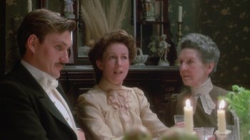 Movie still from “The Dead” (1987), directed by John Huston – A group of people sitting around a table with a candle; Medium shot, Over the shoulder angle