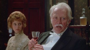 Movie still from “The Dead” (1987), directed by John Huston – An older man holding a glass of wine in front of a woman; Close Up shot, Over the shoulder angle