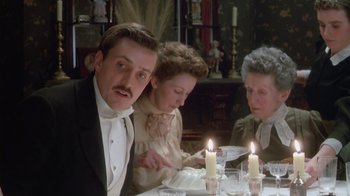 Movie still from “The Dead” (1987), directed by John Huston – A group of people sitting around a table with candles; Medium shot, Low angle