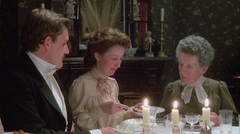 Movie still from “The Dead” (1987), directed by John Huston – A group of people sitting around a table with a cake; Medium shot, High angle