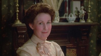 Movie still from “The Dead” (1987), directed by John Huston – A woman in a victorian dress sitting in front of a fireplace; Close Up shot, High angle