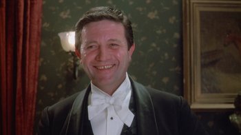 Movie still from “The Dead” (1987), directed by John Huston – A man in a tuxedo smiling for the camera; Close Up shot, Low angle