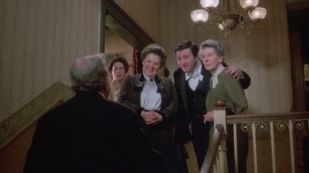 Movie still from “The Dead” (1987), directed by John Huston – A group of people standing next to each other in front of a railing; Medium shot, High angle
