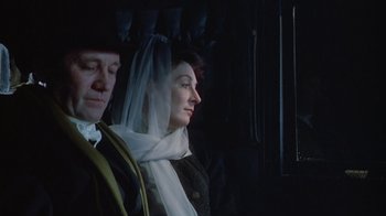 Movie still from “The Dead” (1987), directed by John Huston – A man and a woman are sitting in a dark room; Close Up shot, Low angle