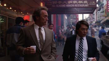 Movie still from “The Dead Pool” (1988), directed by Buddy Van Horn – A man in a suit and tie walking down a street; Medium shot, Over the shoulder angle