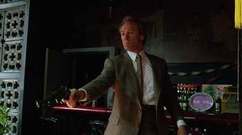 Movie still from “The Dead Pool” (1988), directed by Buddy Van Horn – A man in a suit and tie holding something in his hand; Medium shot, Low angle