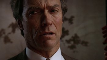 Movie still from “The Dead Pool” (1988), directed by Buddy Van Horn – An older man in a suit and tie looking at the camera; Close Up shot, Low angle