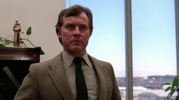 Movie still from “The Dead Pool” (1988), directed by Buddy Van Horn – A man wearing a suit and tie in front of a window; Close Up shot, Low angle