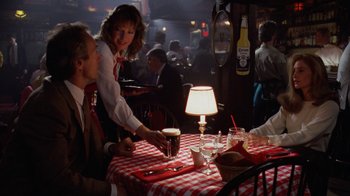 Movie still from “The Dead Pool” (1988), directed by Buddy Van Horn – A group of people sitting at a table in a restaurant; Medium shot, Over the shoulder angle