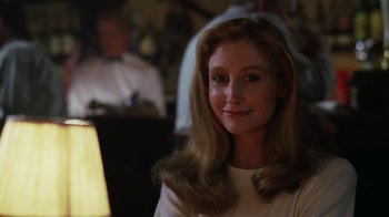 Movie still from “The Dead Pool” (1988), directed by Buddy Van Horn – A woman with long blonde hair sitting in front of a lamp; Close Up shot, Over the shoulder angle
