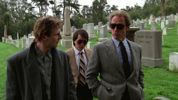 Movie still from “The Dead Pool” (1988), directed by Buddy Van Horn – A group of men standing next to each other in a cemetery; Medium shot, Low angle