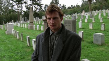 Movie still from “The Dead Pool” (1988), directed by Buddy Van Horn – A man standing in front of a grave in a cemetery; Medium shot, Low angle