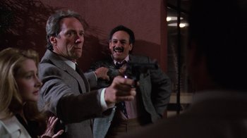 Movie still from “The Dead Pool” (1988), directed by Buddy Van Horn – Two men in suits and ties are holding guns; Medium shot, Over the shoulder angle