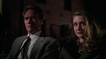 Movie still from “The Dead Pool” (1988), directed by Buddy Van Horn – A man and a woman sitting next to each other in front of a brick wall; Close Up shot, Low angle