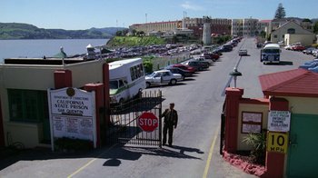 Movie still from “The Dead Pool” (1988), directed by Buddy Van Horn – A man standing in a parking lot next to a stop sign; Extreme Wide shot, High angle