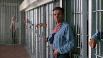 Movie still from “The Dead Pool” (1988), directed by Buddy Van Horn – A man leaning against a wall in front of a jail cell; Medium shot, Low angle