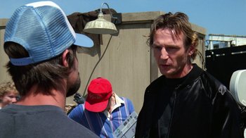 Movie still from “The Dead Pool” (1988), directed by Buddy Van Horn – A man wearing a red hat talking to two other men; Close Up shot, Over the shoulder angle