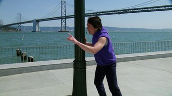 Movie still from “The Dead Pool” (1988), directed by Buddy Van Horn – A man standing next to a pole near the water; Wide shot, Over the shoulder angle