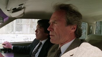 Movie still from “The Dead Pool” (1988), directed by Buddy Van Horn – Two men sitting in the back seat of a car; Close Up shot, Low angle
