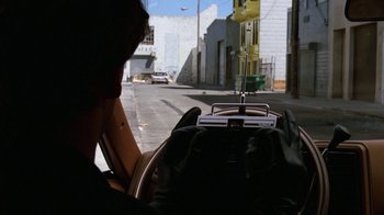 Movie still from “The Dead Pool” (1988), directed by Buddy Van Horn – A person driving a car down a street; Close Up shot, Over the shoulder angle