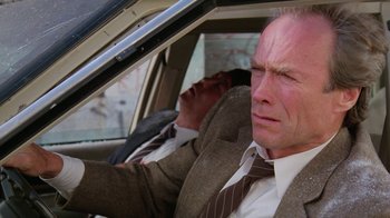 Movie still from “The Dead Pool” (1988), directed by Buddy Van Horn – A man in a suit and tie sitting in the driver's seat of a car; Close Up shot, Low angle
