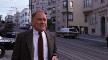 Movie still from “The Dead Pool” (1988), directed by Buddy Van Horn – An older man wearing a suit and tie standing on the side of the street; Medium shot, High angle