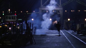 Movie still from “The Dead Pool” (1988), directed by Buddy Van Horn – A person is walking on a bridge with smoke coming out of it; Extreme Wide shot, Over the shoulder angle