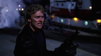 Movie still from “The Dead Pool” (1988), directed by Buddy Van Horn – A man in a black jacket holding a gun; Close Up shot, Over the shoulder angle