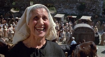 Movie still from “The Decameron” (1971), directed by Pier Paolo Pasolini – An old woman smiling in front of a crowd of people; Close Up shot, Low angle