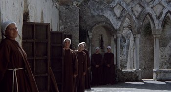 Movie still from “The Decameron” (1971), directed by Pier Paolo Pasolini – A group of nuns standing next to each other in front of an old building; Wide shot, Low angle