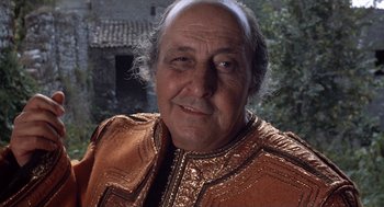 Movie still from “The Decameron” (1971), directed by Pier Paolo Pasolini – An older man wearing a brown jacket and white beard; Close Up shot, Low angle