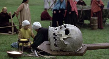 Movie still from “The Decameron” (1971), directed by Pier Paolo Pasolini – A skull is sitting on top of a wooden board; Close Up shot, High angle