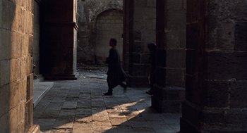 Movie still from “The Decameron” (1971), directed by Pier Paolo Pasolini – Two people walking in an alley way in the sunlight; Wide shot, High angle