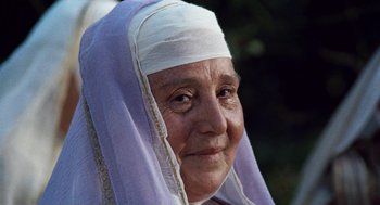 Movie still from “The Decameron” (1971), directed by Pier Paolo Pasolini – An older woman wearing a white head covering; Close Up shot, Low angle