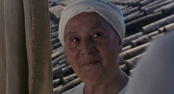 Movie still from “The Decameron” (1971), directed by Pier Paolo Pasolini – An older woman wearing a white turban is looking at the camera; Close Up shot, Over the shoulder angle