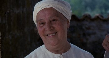 Movie still from “The Decameron” (1971), directed by Pier Paolo Pasolini – An older woman wearing a white turban and smiling; Close Up shot, Low angle