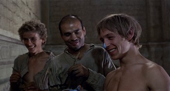 Movie still from “The Decameron” (1971), directed by Pier Paolo Pasolini – A group of people standing next to each other in a room; Medium shot, Low angle